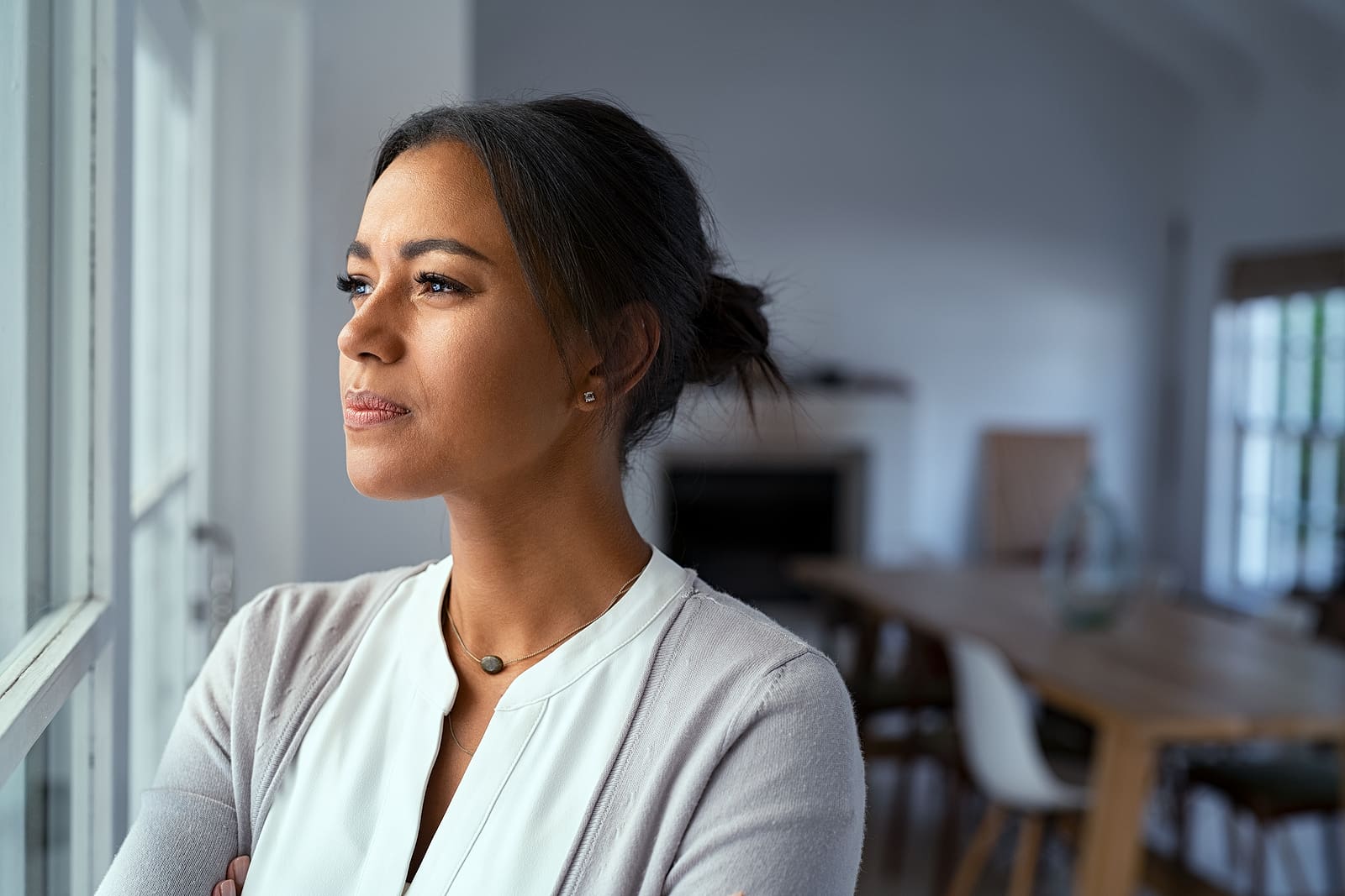 Mature african woman looking outside window with uncertainty. Th